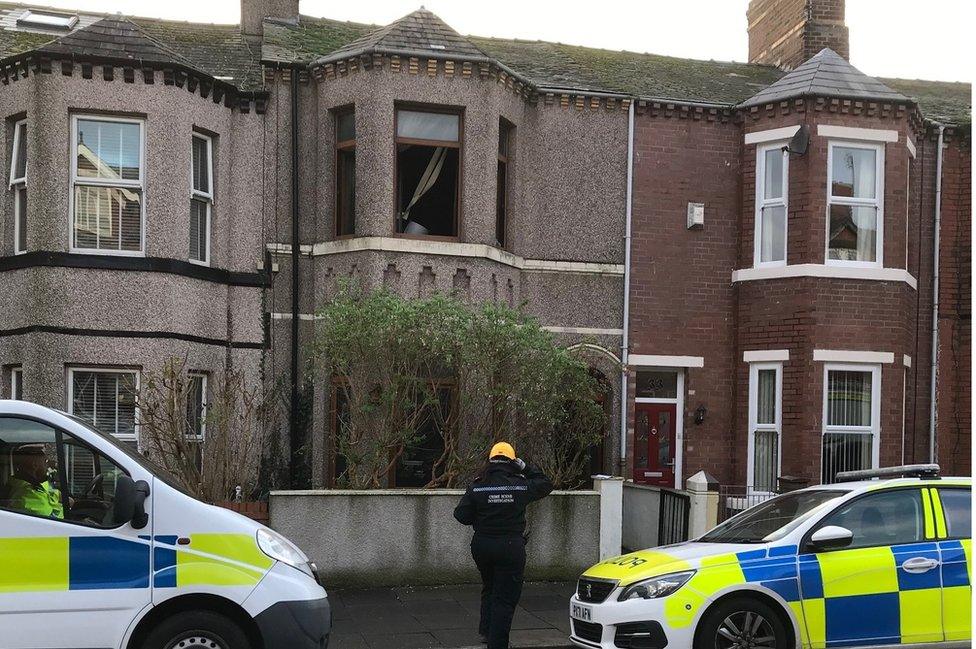 Police cars and officer outside terraced house where fire was