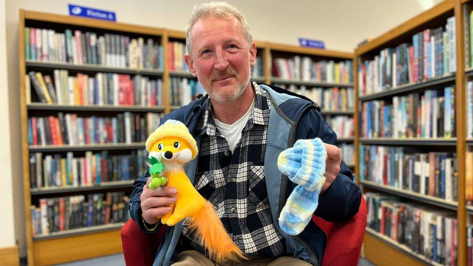 Sergei Sogokon holding a knitted hat and toy fox