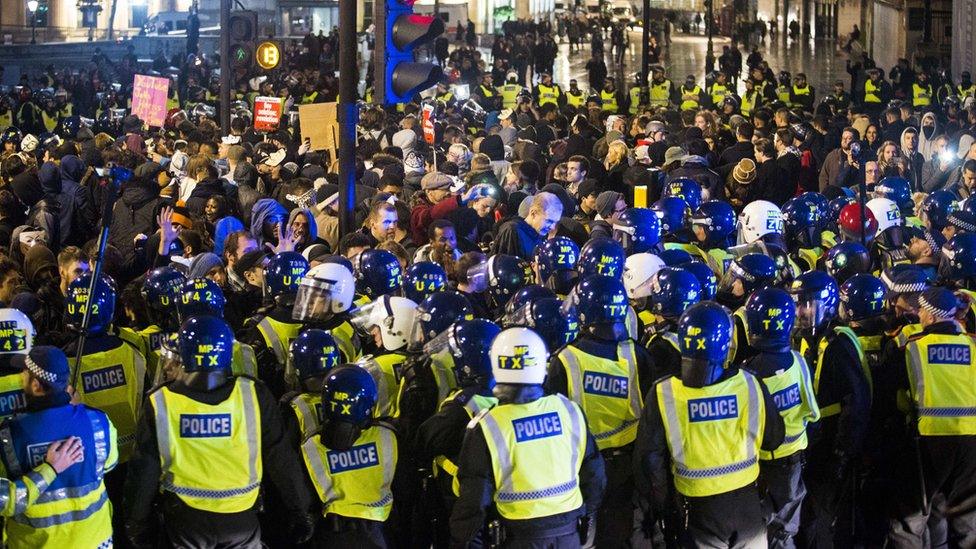 A crowd composed of police and civilians group together in London