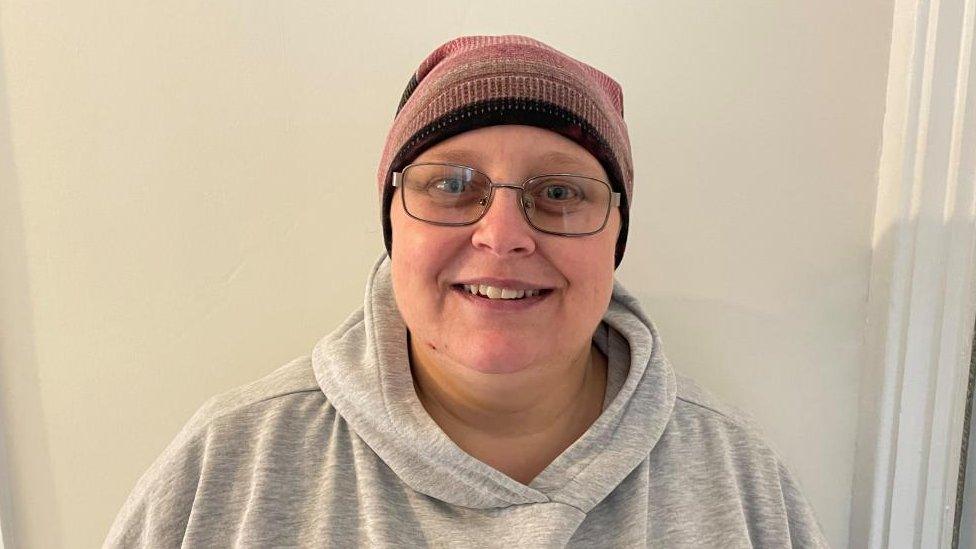 Woman wearing woollen hat and glasses with a grey hoodie