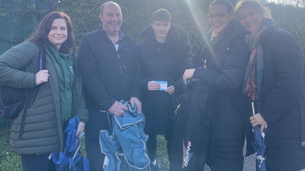 A family holding tickets for the match and chairs