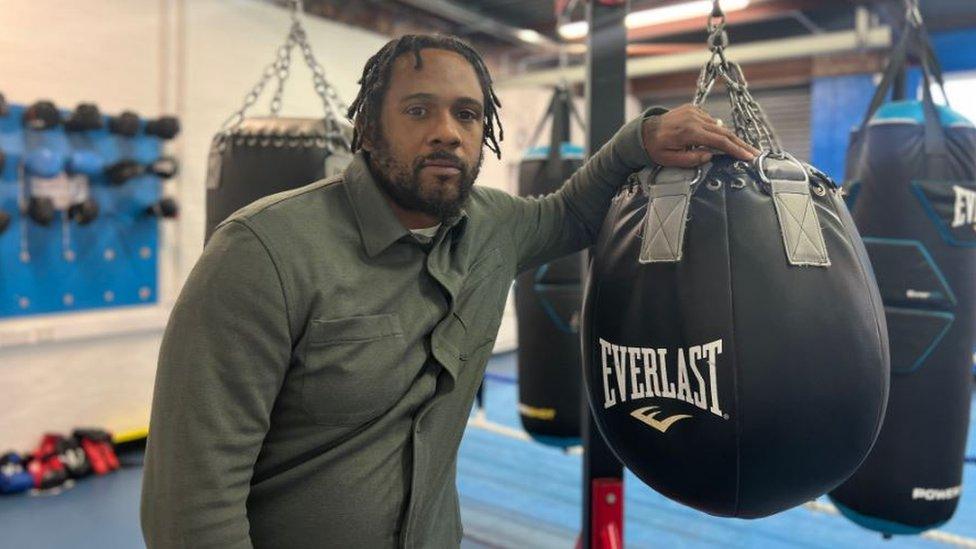 Dayton Powell leaning up against a punching bag in Empire Fighting Chance boxing gym