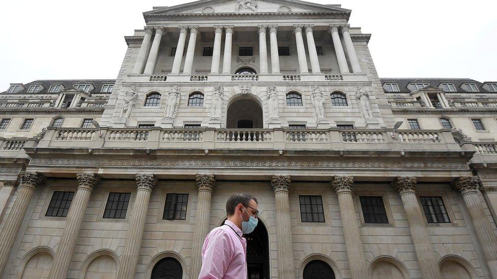 Man wearing a mask walks passed the Bank of England in the City of London