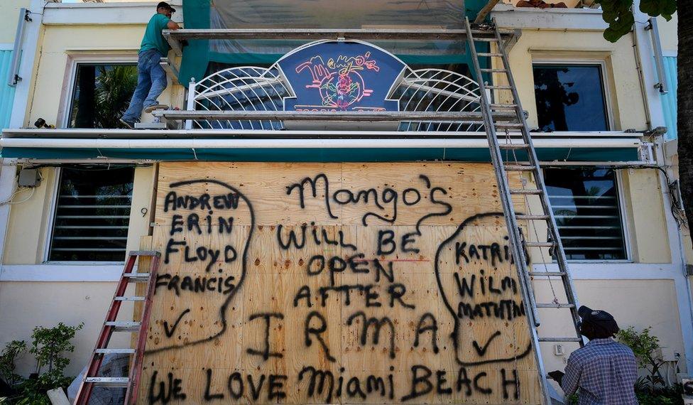 A worker covers the windows of a restaurant with plywood in preparation for Hurricane Irma, Miami Beach, Florida, 7 September 2017