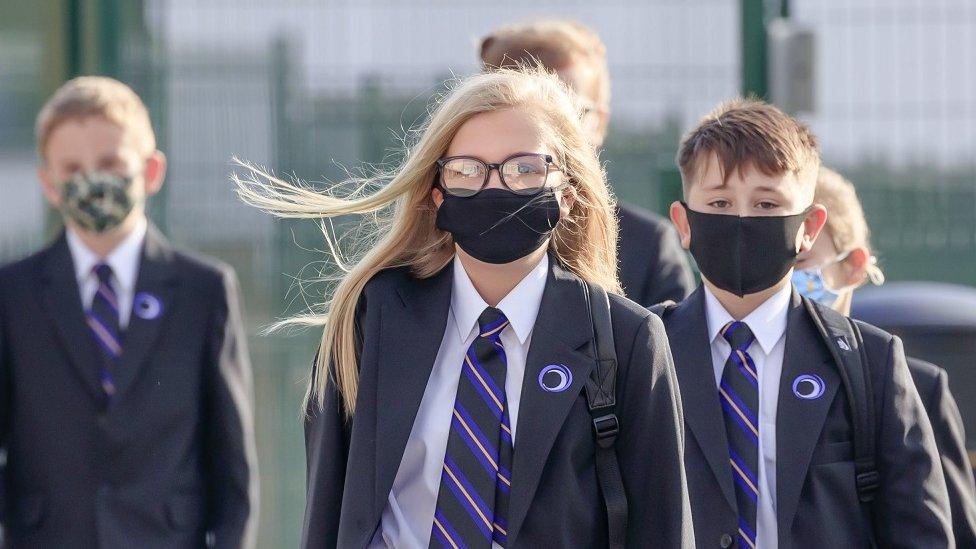 Children in face masks walk into school