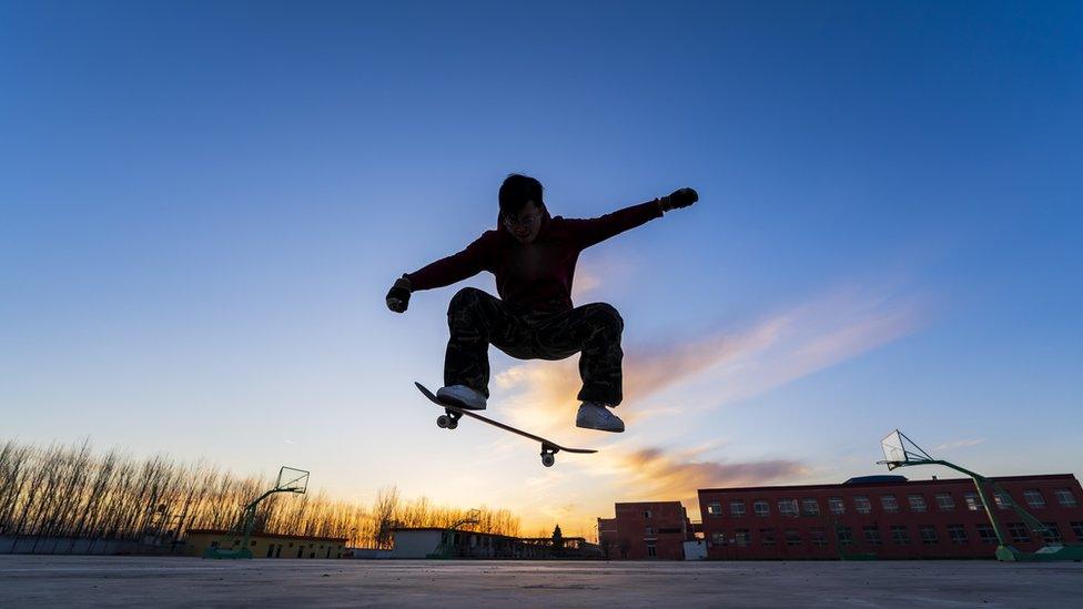 Shadow of someone in the air skateboarding seen against a sunset