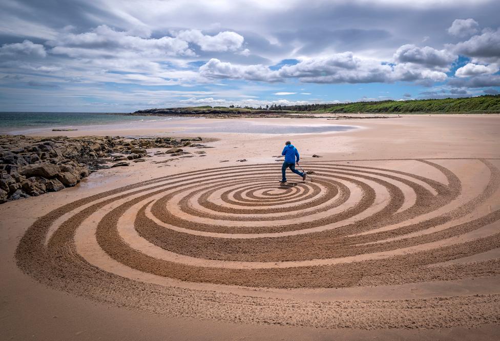 Artist Sean Corcoran, from Waterford, Ireland, creates a piece of sand art on the beach at Tyninghame, East Lothian, during the European Land Art Festival in Scotland. 4 July 2022.