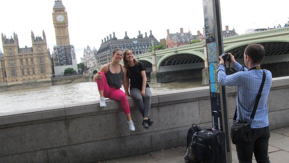 A man taking two women's photograph