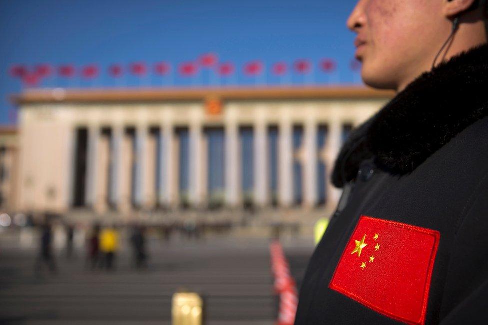 In this 12 March 2017 photo, a security official with a Chinese flag patch on his jacket stands guard outside of the Great Hall of the People before a plenary session of the National People's Congress (NPC) in Beijing, China.