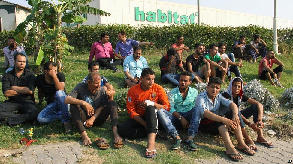 Factory workers in Egypt look on as a fire burns