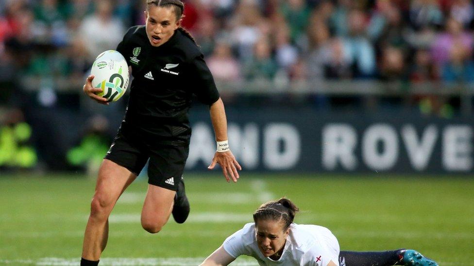 New Zealand player runs with the ball while England player chases unsuccessfully.