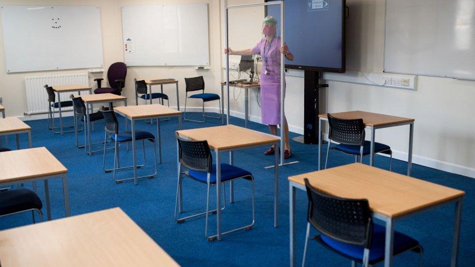 An empty classroom and woman in mask