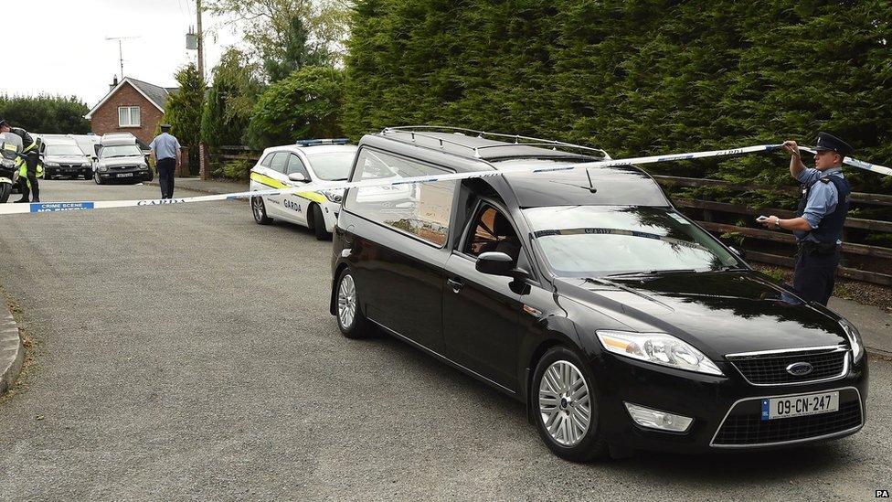 A Garda officer lifts tape as a hearse leaves the scene in Ballyjamesduff, Cavan, 29 August 2016