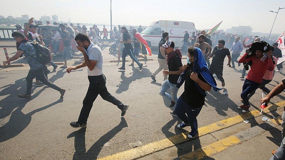 Iraqi protesters run for cover as security forces use tear gas to disperse the crowd in central Baghdad during anti-government demonstrations in the Iraqi capital on October 25, 2019