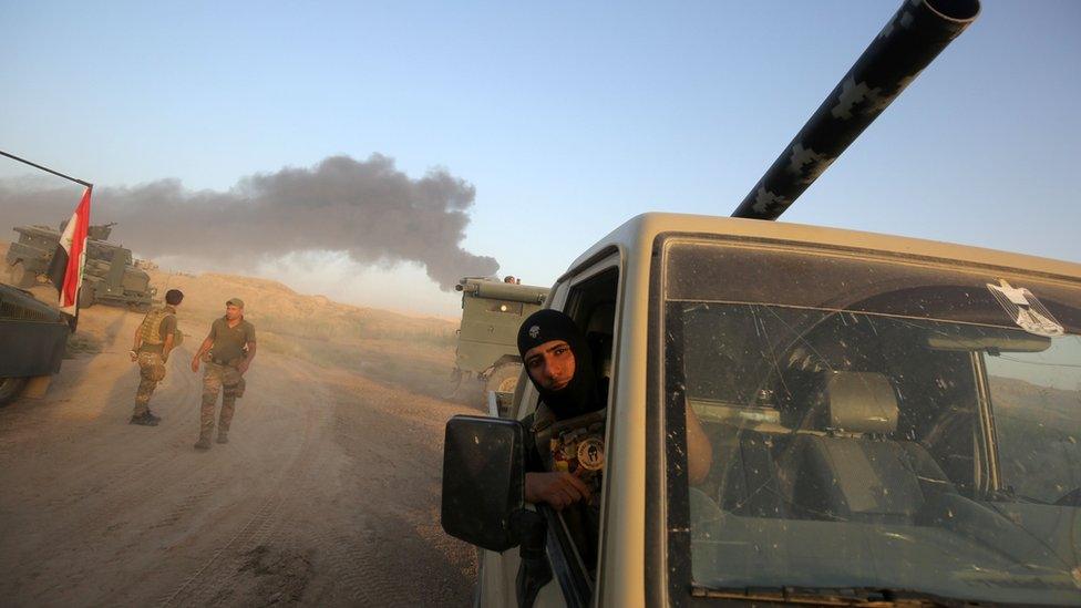 Smoke billows in the background as Iraqi pro-government forces advance towards the city of Fallujah on May 23, 2016,