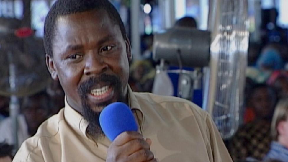 TB Joshua holding a blue microphone