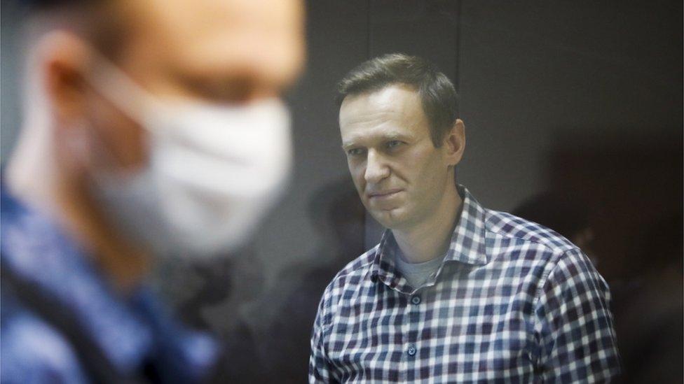 A masked police officer stands in front of Alexei Navalny during a court hearing in February 2021