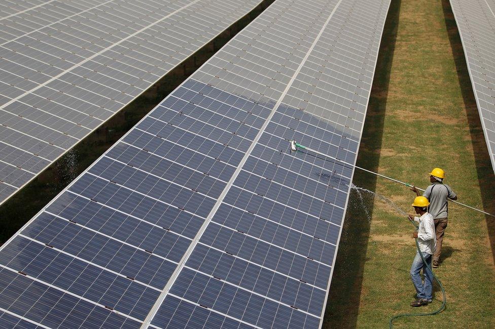 Workers clean solar panels in Gujarat, India