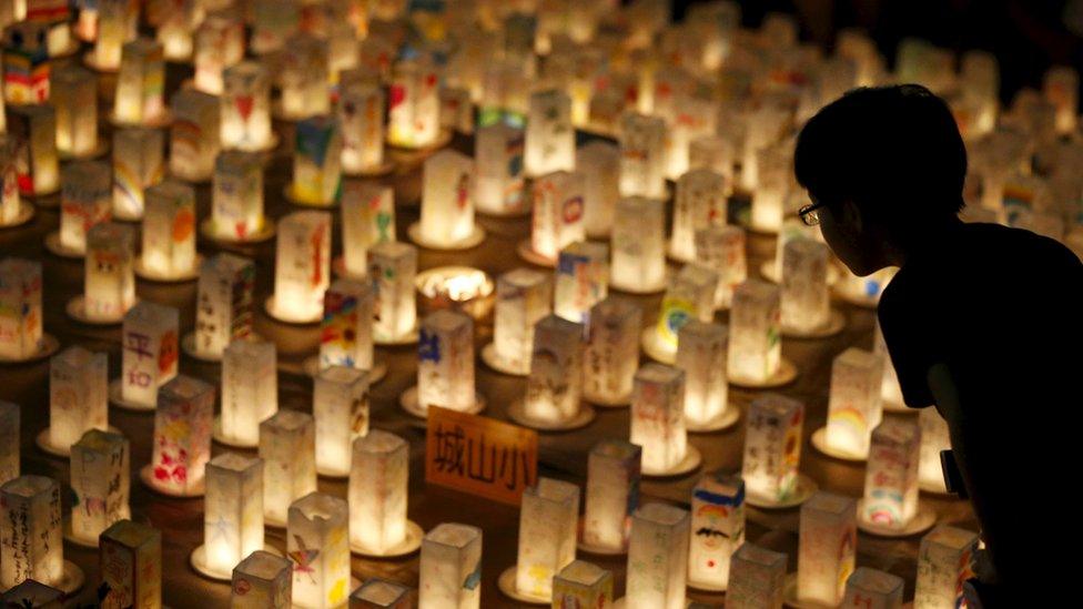 A boy looks at candles during a candlelit memorial event to mourn the victims of the 1945 atomic bombing at Nagasaki's Peace Park