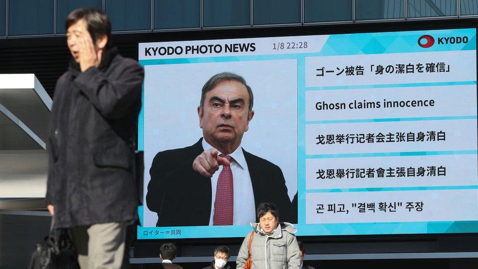 Pedestrians walk past giant TV screen