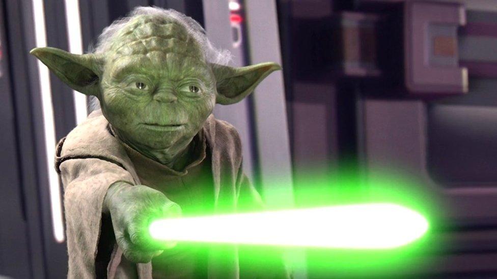 Yoda with lightsaber ignited.