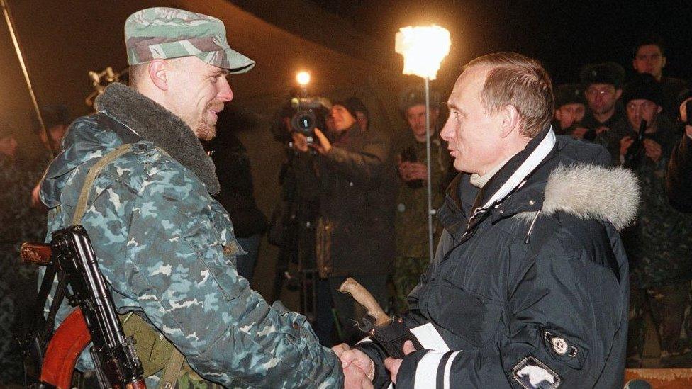 Acting Russian President Vladimir Putin shakes hands with a Russian officer as he presents an ornamental hunting knife during an awarding ceremony in Gudermes