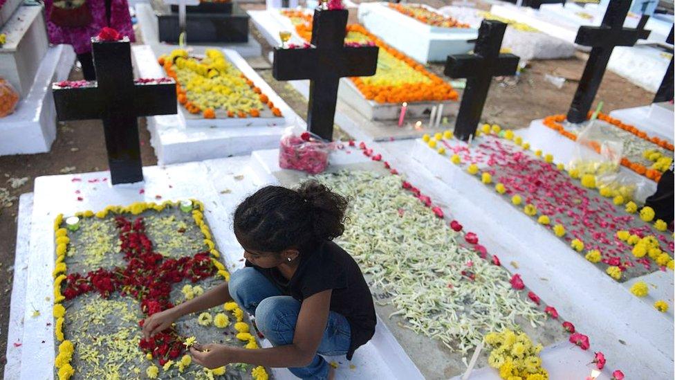 An Indian Christian girl decorates the graves of deceased family members at a Catholic cemetery during All Souls Day in Hyderabad