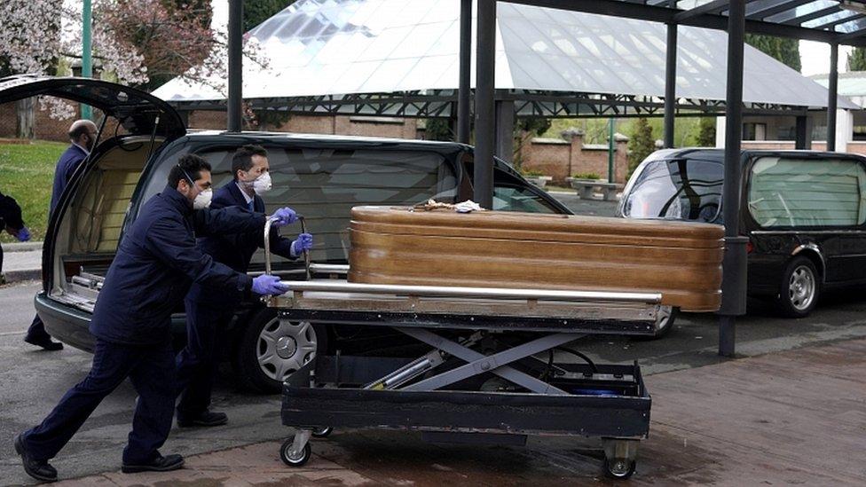 Employees of a mortuary enter the crematorium of La Almudena cemetery with a coffin of a person who died of coronavirus disease in Madrid, March 23, 2020