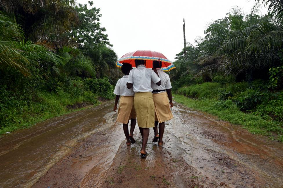 Three schoolgirls walks home in a countryside village of Sierra Leone on 12 July 2019.