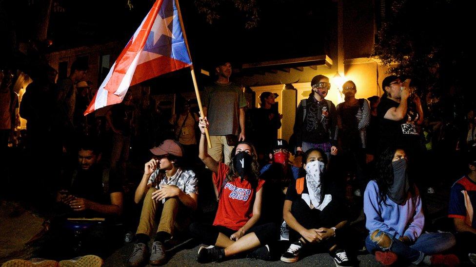 Demonstrators sit in to block the exit of Pedro Pierluisi's convoy after his first news conference as governor of Puerto Rico