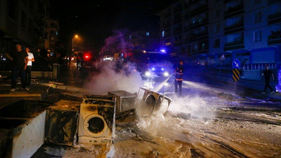 A firefighter extinguishes goods of a shop burnt during riots against refugees in Ankara, Turkey