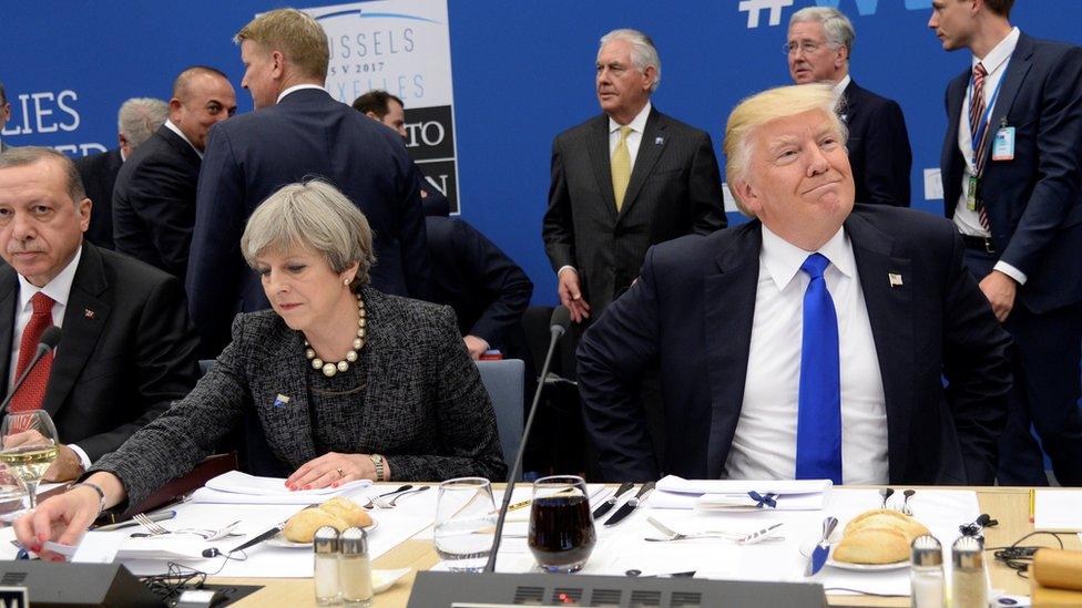 US President Donald Trump (R) reacts as he sits next to Britain"s Prime Minister Theresa May (C) and Turkish President Recep Tayyip Erdogan (L) during a working dinner meeting at the NATO summit in Brussels, Belgium, 25 May 2017