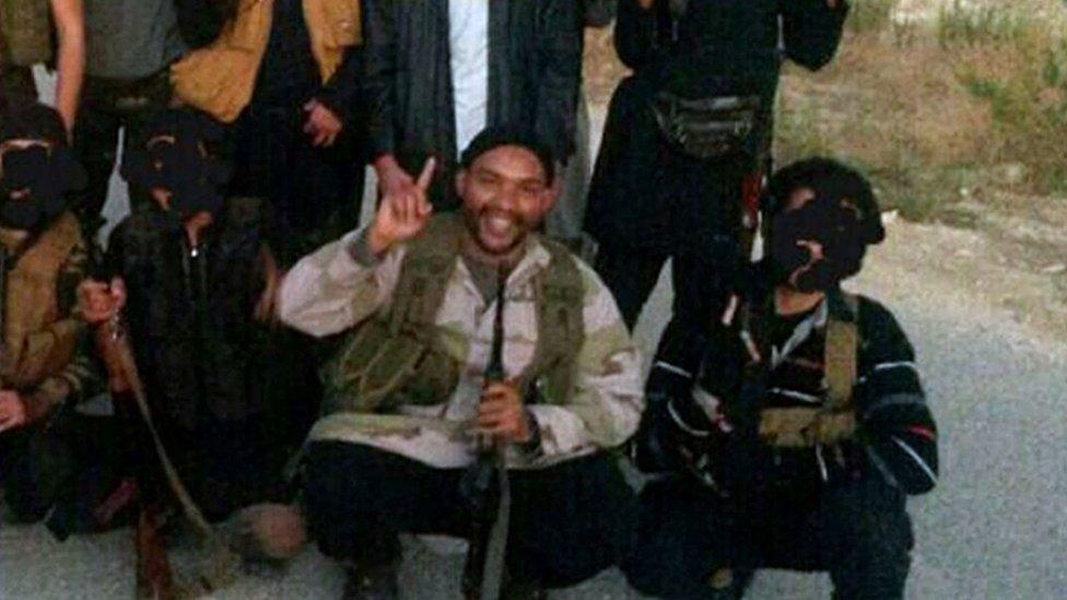 Aine Davis in Syria posing with a group of men while holding a gun