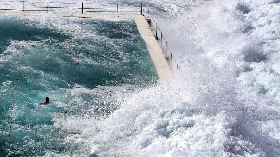 A swimmer at Bondi's ocean pool watches as a big wave pours into the pool as large seas pound the coast at Bondi Beach in Sydney on March 6, 2017