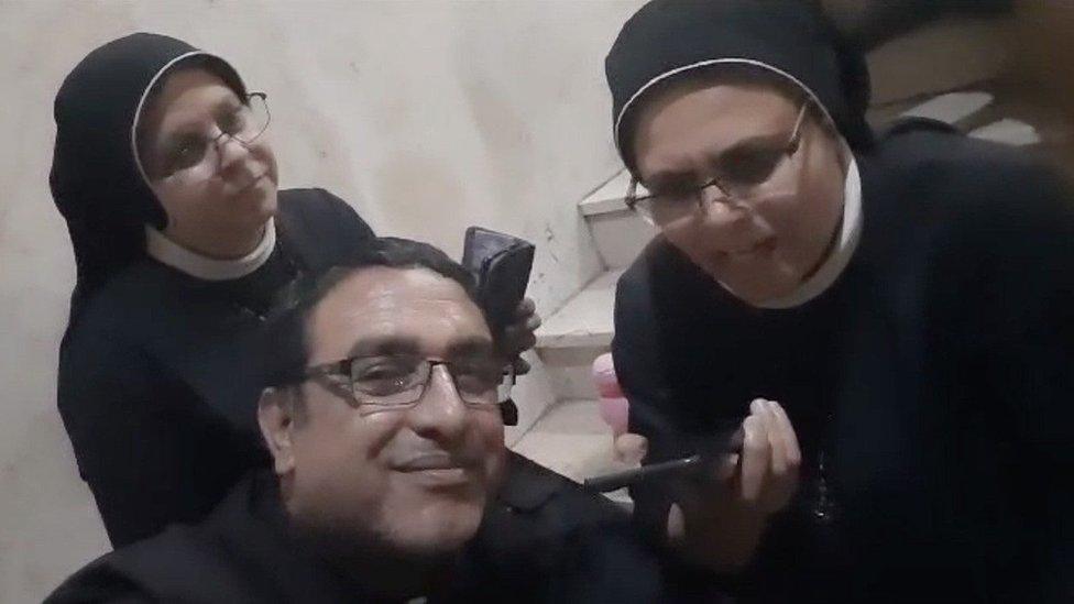 Sister Nabila Saleh (R) and Father Yusuf Asad (C) talk to the Pope by telephone from Gaza City's Holy Family Church