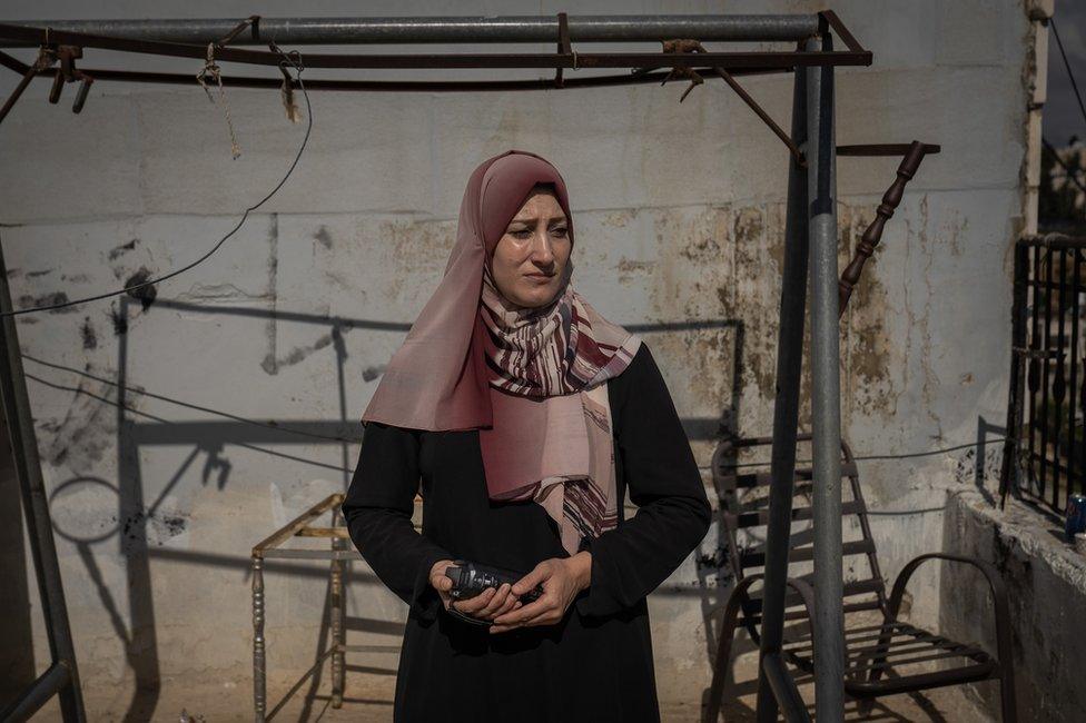 Areej Jabari holds her video camera on her rooftop in H2. "The goal is to divide us, to pressure us to leave," she said.