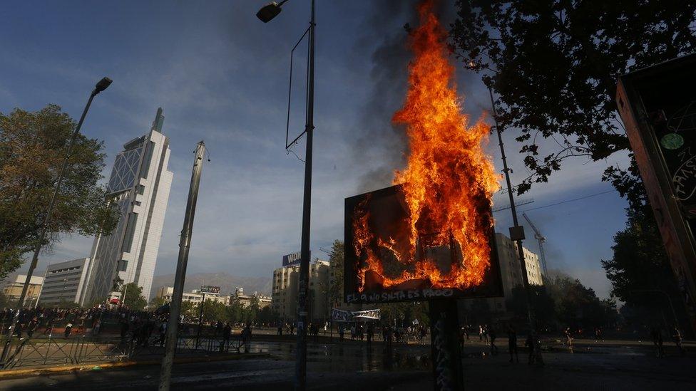 Demonstrators light fires as clashing with riot police during a protest on October 21, 2019 in Santiago, Chile