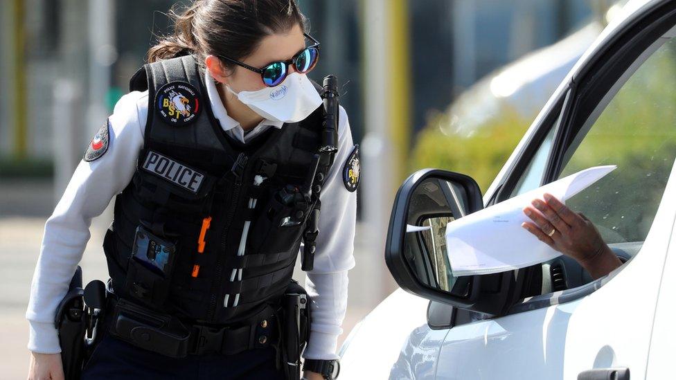 A French police officer looks at a piece of paper held by a motorist at a checkpoint on the Promenade des Anglais in Nice (6 April 2020)