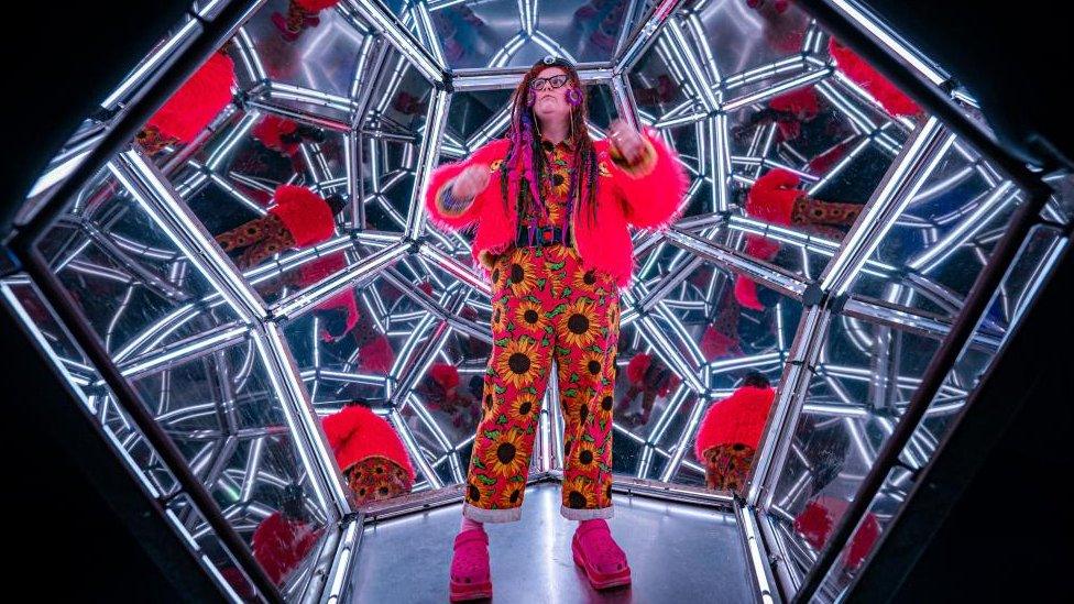 Woman standing inside room of mirrors at Wake The Tiger