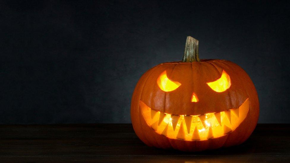 A Halloween pumpkin with a scary face in a dark room