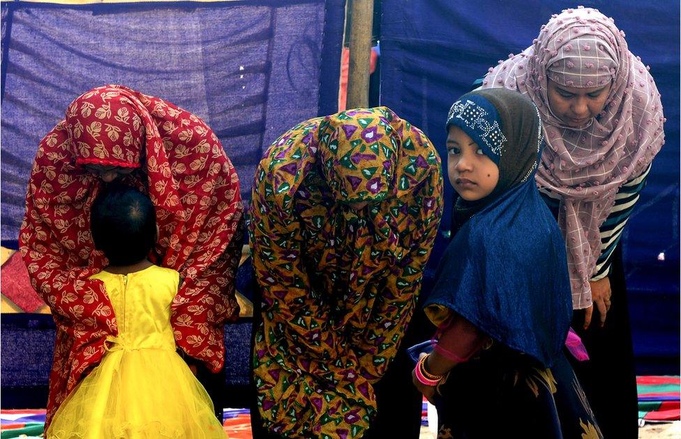 A child looks on as women offer Eid al-Adha prayers