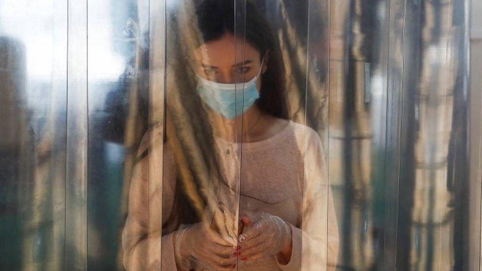 A woman wearing a protective face mask and gloves walks through a disinfection cabin at the entrance to a shopping centre in Moscow, Russia. Photo: 5 June 2020