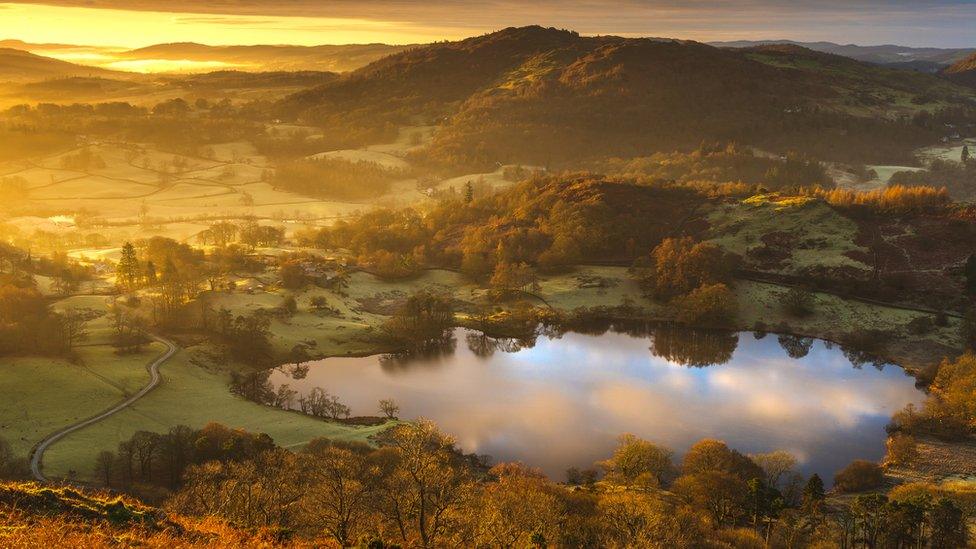 Small lake surrounded by hills with sunrise