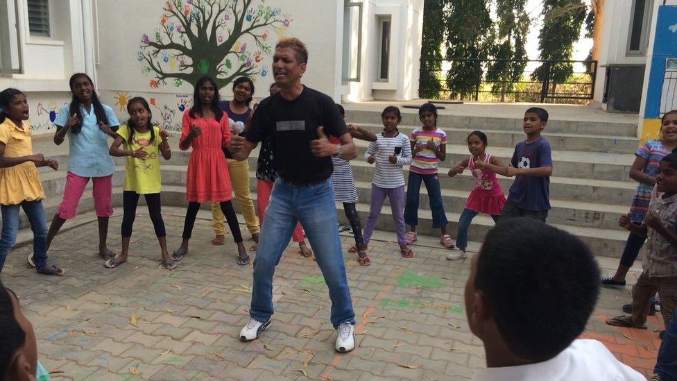 Mr Rego singing and dancing with children at the home