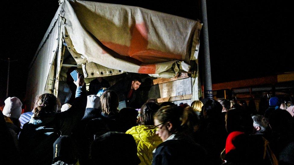 People who flee Mariupol and Melitopol wait around an evacuee cargo truck at a collecting point in Zaporizhzhia