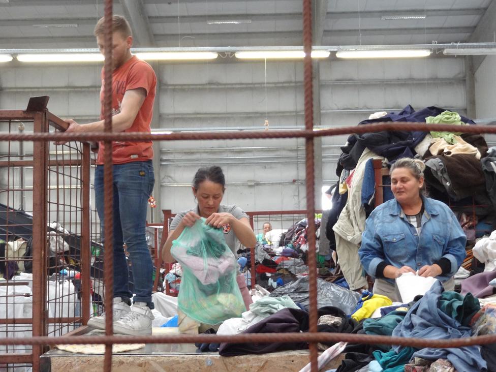 Clothes sorters viewed through the bars of a cage