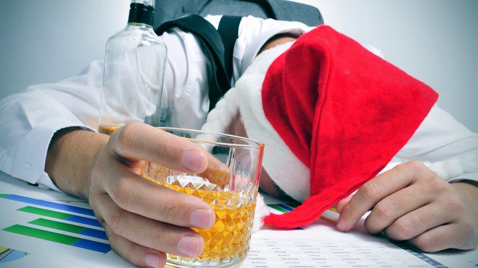 Man with drink sleeping at desk after Christmas party