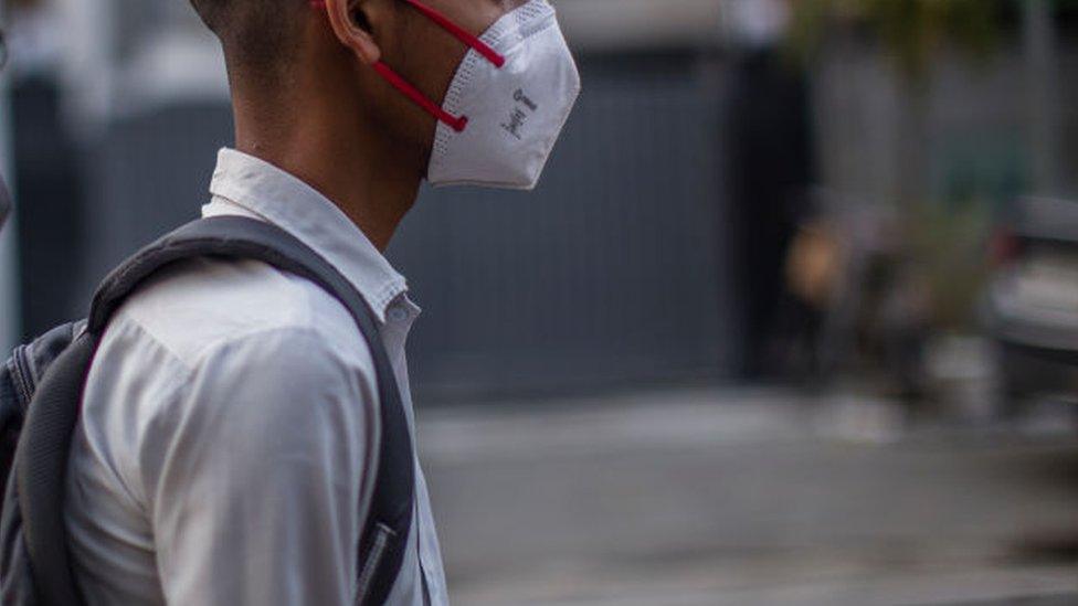 A Delhi school boy with a shoulder bag looks on