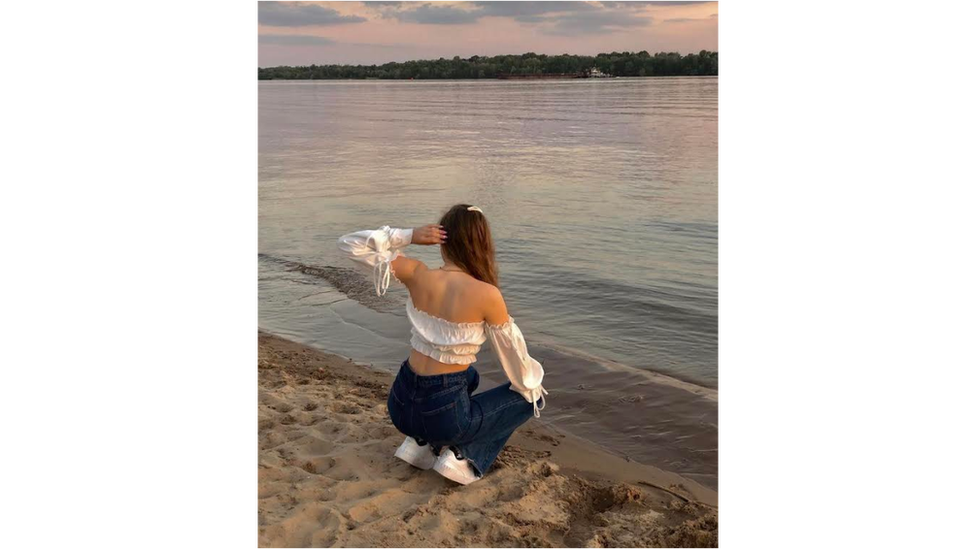 Teeanger girl crouching by river in Ukraine