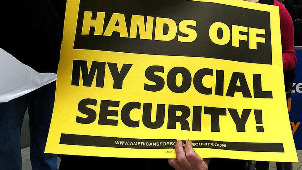 Bob Ducharme participates displays a sign during a demonstration in front of the Social Security Administration office